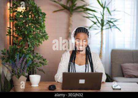 Giovane donna adulta che ama la musica a distanza e lavora a casa Foto Stock