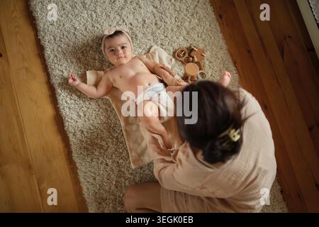Intimità e cura definiscono questa scena, una madre e un bambino in una tranquilla coccola, circondati da tessuti morbidi. Mostra lo spirito gentile della genitorialità. Foto Stock
