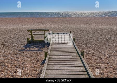 Passerella in legno con panca all'estremità che si affaccia sul mare. Foto Stock
