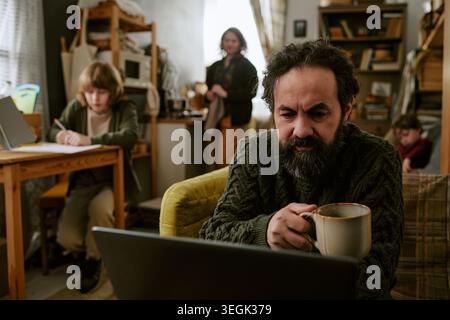 Uomo di mezza età che lavora su un notebook in difficoltà finanziarie a casa Foto Stock