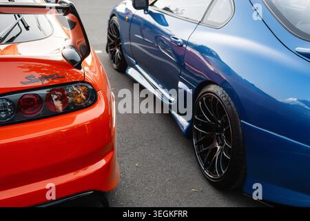 Un paio di auto sportive Toyota Supra A80 affiancate - una arancione e una blu. Vista ravvicinata posteriore e laterale di due auto sportive giapponesi Totota Supra mk4 Foto Stock