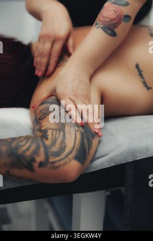 Le mani massaggiano il braccio di una persona con cura e precisione Foto Stock