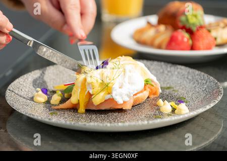 Delizioso piatto per la colazione con uova in camicia e vivaci decorazioni in un Sunny Café Foto Stock
