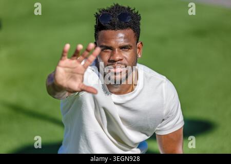 Un uomo afroamericano attivo sui 30 anni con la mano in avanti in un parco pubblico, vestito da una maglietta bianca. Foto Stock