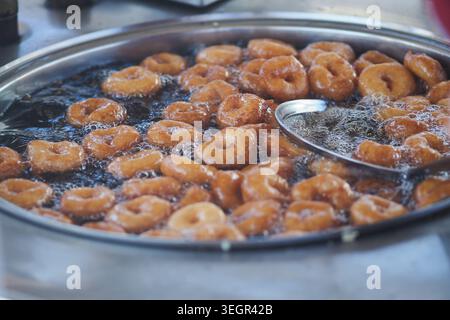 Le ciambelle turche friggono in olio caldo in uno stand di cibo di strada Foto Stock