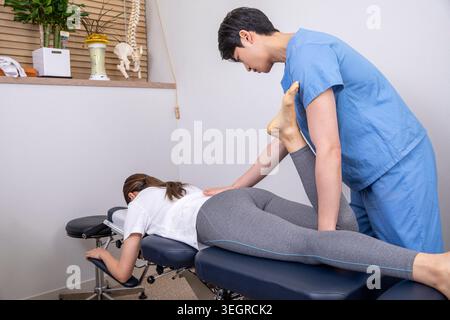 Un medico sta esaminando la schiena di un paziente su un tavolo chiropratica in una clinica medica. Foto Stock