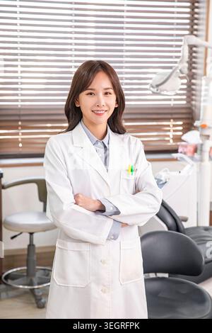 Un dentista sorridente che indossa un camice da laboratorio bianco e si trova in una moderna clinica odontoiatrica. Foto Stock