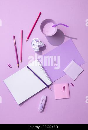 Un vivace spazio di lavoro color pastello, con una varietà di strumenti e materiali, è predisposto per un progetto creativo. Foto Stock