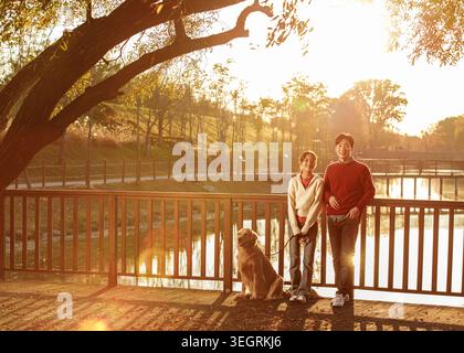 Una giovane coppia e il loro cane si godono un pomeriggio di sole in un parco tranquillo. Foto Stock