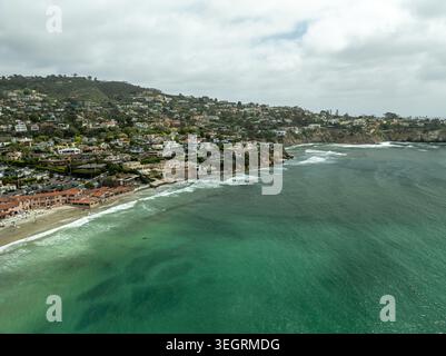 Veduta aerea di la Jolla Cove con acque turchesi dell'oceano, onde infranti e residenze costiere sulle colline di San Diego, California, United Foto Stock