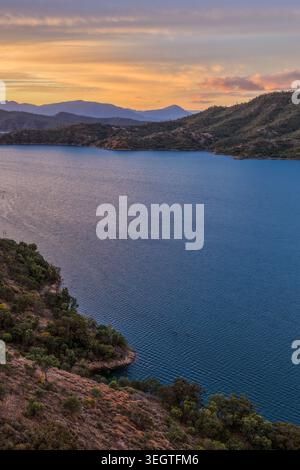 Vista verticale aerea della diga di Glenbawn al tramonto nel nuovo Galles del Sud Australia. La fotografia con i droni cattura le acque calme della diga, le colline circostanti e il cielo colorato. Foto Stock