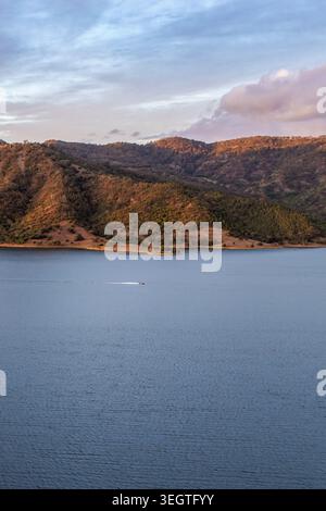 Vista verticale aerea della diga di Glenbawn e della catena montuosa circostante con una barca che scivola sull'acqua nel nuovo Galles del Sud Australia. Fotografia con i droni. Foto Stock