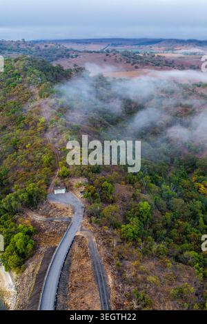 Vista verticale dall'alto della sede della valvola di Glenbawn Dam con la nebbia che attraversa il paesaggio circostante della valle nel nuovo Galles del Sud Australia. Foto Stock