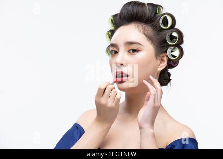 Una donna applica il rossetto in uno studio di bellezza. Foto Stock