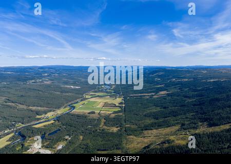 Una vista aerea mozzafiato di un'ampia valle fluviale che si estende in lontananza sotto un vasto e limpido cielo blu. Un fiume tortuoso scorre attraverso t Foto Stock