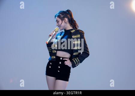 Una cantante femminile si esibisce sul palco, tenendo un microfono e cantando al pubblico. Foto Stock