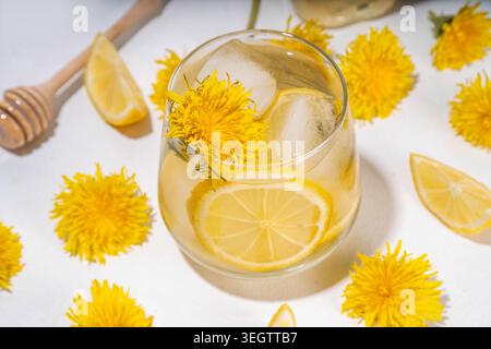 Tè freddo o limonata. Pianta bevanda floreale a base di erbe con leoni fiori e radici, limone e sciroppo, su sfondo bianco copia spa Foto Stock
