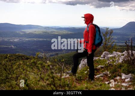 Donna in piedi sulla cima di Veliki Kozljek sulla catena montuosa di Javorniki, sulla costa slovena e italiana sul retro, Slovenia Foto Stock