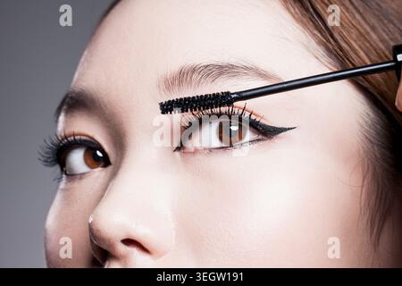 Primo piano della faccia di una giovane donna che mette il mascara Foto Stock