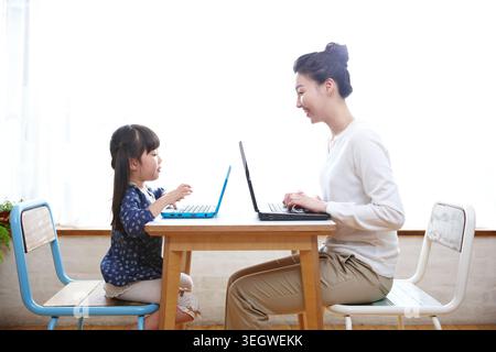 Madre e figlia utilizzando computer portatili sul tavolo Foto Stock