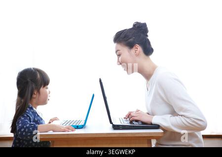 Madre e figlia utilizzando computer portatili sul tavolo Foto Stock