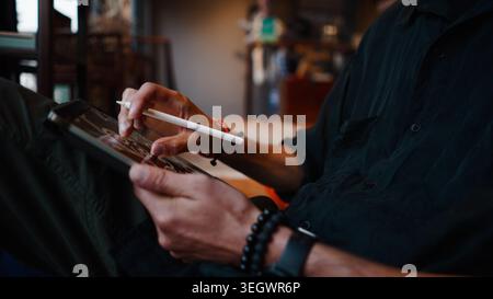 Artista che crea arte digitale su un tablet utilizzando uno stilo per il design Foto Stock