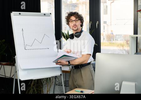 Bel giovane si impegna attivamente con i colleghi mentre presenta un progetto in un ufficio luminoso. Foto Stock
