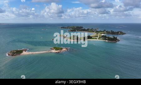 Vista aerea delle lussureggianti isole verdi e delle acque turchesi della Baia di Morlaix, con spiagge sabbiose e affioramenti rocciosi sotto un cielo nuvoloso a cara Foto Stock