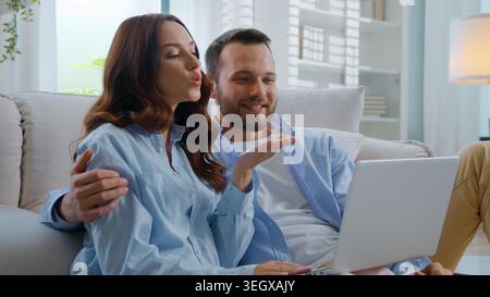 Felice saluto di coppia caucasica invio bacio aria ciao videochiamata parlante con webcam per laptop sorridere emotivo conversazione remota felice discorso di famiglia Foto Stock