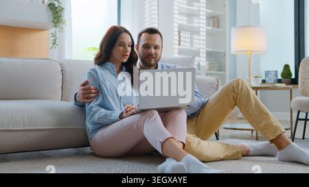Caucasica coppia felice parlare usando il portatile insieme discutere di acquisti uomo sposato con donna che cerca in computer parlare parlare parlare di pianificazione Foto Stock