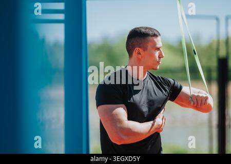 Uomo che si allena con una fascia di resistenza all'aperto per allenarsi con forza e fitness Foto Stock