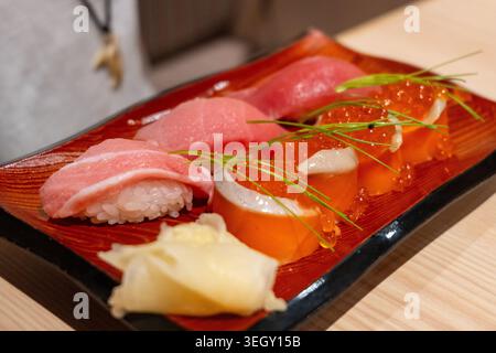 Un elegante piatto di sushi nigiri con tonno, salmone e uova, servito in un ristorante di Tokyo con guarnigione e zenzero sottaceto Foto Stock