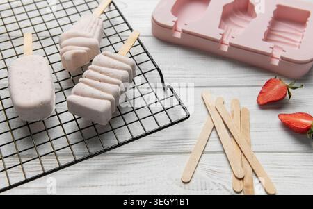 Tre fragole essiccate su una griglia con una muffa rosa e fragole fresche Foto Stock