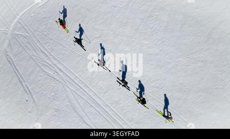 Veduta aerea di un gruppo di sciatori che sale su una pista innevata vicino a Pointe Percee con lunghe ombre e piste sulla neve bianca le Reposoir, Auvergne-Rodano Foto Stock