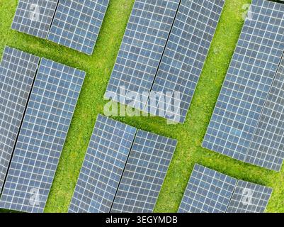 Vista aerea dei pannelli solari disposti in file su un lussureggiante campo verde ad Aiglsbach, Baviera, Germania. Foto Stock