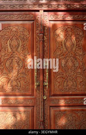Le porte in legno splendidamente intagliato mostrano disegni dettagliati illuminati dalla luce soffusa del sole. Kiev, Ucraina, 21 maggio 2026 Foto Stock