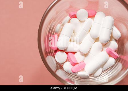 Pillole e capsule assortite in un recipiente di vetro in primo piano. Concetto di farmaco farmaceutico e trattamento sanitario con compresse colorate di medicina. Foto Stock