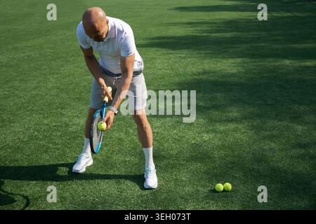 Ritratto a figura intera di un tennista maturo atletico sul campo verde all'aperto. Stile di vita sano, sport estivo attivo e concetto di allenamento professionale Foto Stock