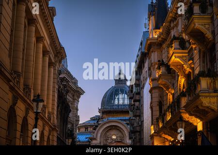 Strada storica illuminata che conduce alla cupola del Palazzo CEC al crepuscolo a Bucarest, Romania Foto Stock