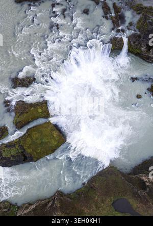 Vista aerea della cascata di Godafoss con potenti acque bianche che si tuffano su rocce vulcaniche scure e muschiate a THingeyjarsveit, Islanda. Foto Stock