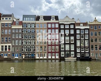 Vista delle tradizionali case strette sui canali con tettoie ornate e grandi finestre che si riflettono sull'acqua di Amsterdam, Paesi Bassi. Foto Stock