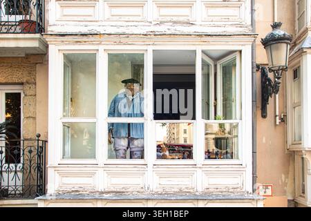 VITORIA-GASTEIZ, SPAGNA - AGOSTO 2025: Un primo piano attraverso una tradizionale finestra a bovindo chiusa in legno, conosciuta come "Mirador", mostra un musicista basco "Blusa" Foto Stock