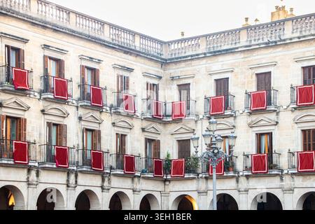 VITORIA-GASTEIZ, SPAGNA - AGOSTO 2025: Stoffe e striscioni tradizionali rosse appese ai balconi di edifici neoclassici storici in t Foto Stock