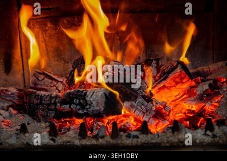 Tronchi di legna da ardere bruciati con fiamme brillanti e brace incandescenti all'interno del caminetto Foto Stock