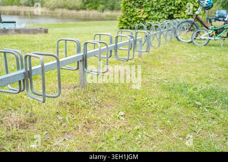 Struttura in acciaio su un prato verde vicino a una zona ricreativa. Supporto ai trasporti ecologici, progettazione urbana, infrastrutture sportive in estate Foto Stock