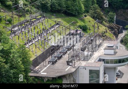Vista aerea della sottostazione elettrica e dell'infrastruttura della centrale elettrica della diga di Verzasca con linee ad alta tensione e lussureggianti colline verdi a Gordol Foto Stock
