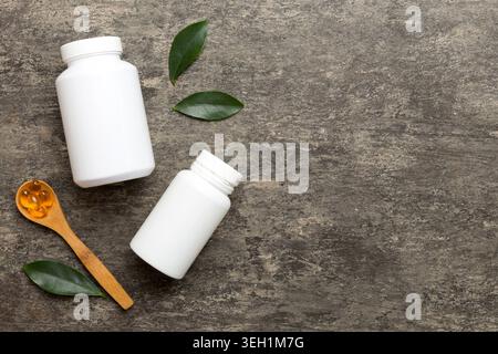 Le capsule di Omega-3 si trovano in un flacone bianco su un tavolo con il fondo verde delle foglie. Compresse di olio di pesce. Additivi biologicamente attivi omega 6, omega 9, vitam Foto Stock