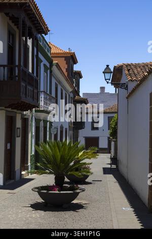 Strada stretta e vuota fiancheggiata da tradizionali balconi in legno ed edifici coloniali bianchi nella storica città di Teror, Gran Canaria. Foto Stock