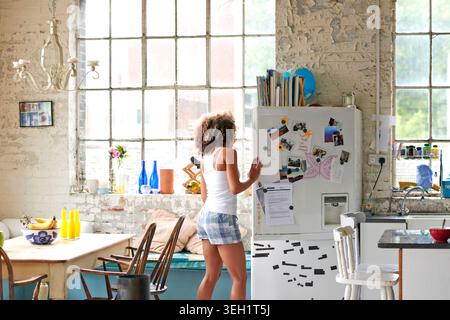 Appartamento, cucina e donna in frigo al mattino per colazione, spuntino e check-out cibo. Al ritorno, durante il fine settimana e la persona aprirono il frigorifero per gli ingredienti Foto Stock