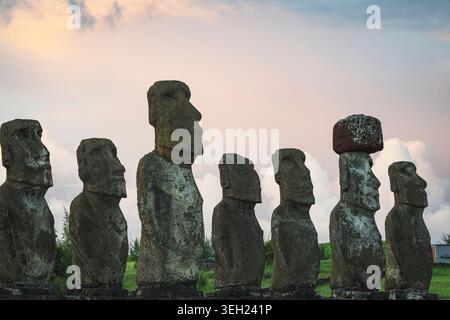 Antiche statue Moai in fila sull'Isola di Pasqua al tramonto Foto Stock